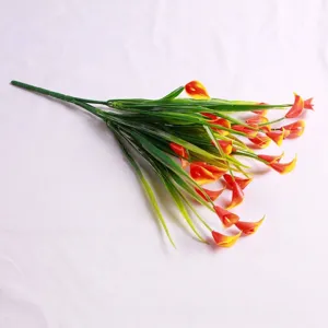Detailed view of artificial orange Calla Lily bouquet with lush green plastic leaves