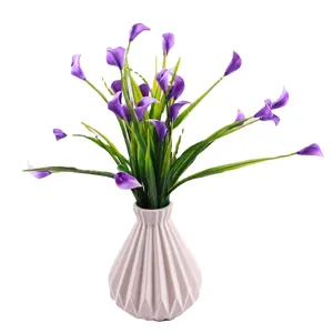 Purple artificial Calla Lily potted plant with green grass in a white faceted vase