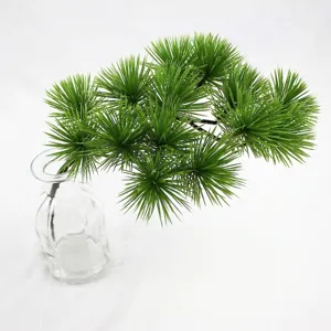 Detail of realistic artificial pine branch greenery in a clear glass vase for decor