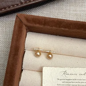 Primer plano de pendientes de perlas doradas con detalles de circonitas brillantes