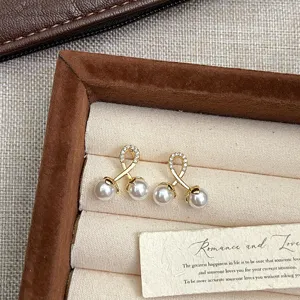 Detalle macro de elegantes pendientes dorados con perlas y acentos de circonita brillante