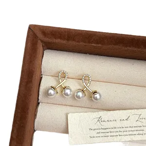 Elegantes pendientes de doble perla dorada con acentos de circón en una caja de regalo