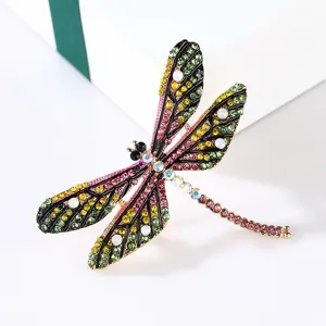 Macro detail of a vintage dragonfly brooch featuring colorful rhinestones and enamel.