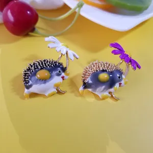 Detailed view of cute hand-painted enamel hedgehog brooches featuring delicate daisy flowers