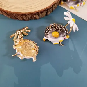 Detailed view of enamel hedgehog brooch with daisy showing both front and back design
