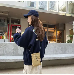 Dettaglio di una borsa a tracolla kaki per cellulare indossata da una modella in stile urbano