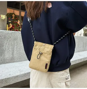 Vista posteriore di una persona con borsa a tracolla a quadretti per cellulare beige