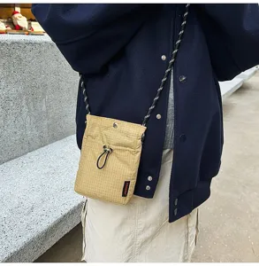 Dettaglio di una mini borsa a tracolla per cellulare leggera a scacchi gialli su un modello