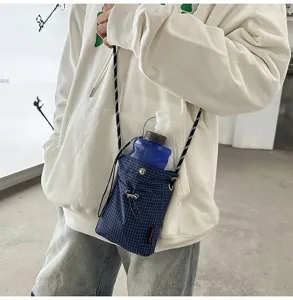 Vista dettagliata di una borsa a tracolla a quadretti blu con una bottiglia d'acqua