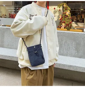 Piccola borsa a tracolla a scacchi blu navy indossata sopra una giacca sportiva bianca
