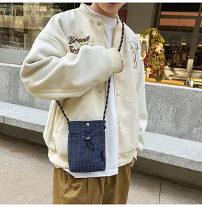 Vista dettagliata di una mini borsa per cellulare a scacchi blu indossata con giacca bianca