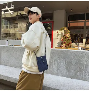 Uomo che indossa una piccola borsa a tracolla per cellulare a scacchi blu navy.