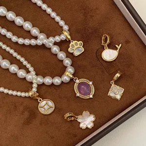 Vue détaillée de pendentifs dorés avec nacre naturelle et zircone dans divers modèles variés.