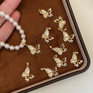 Vue détaillée des pendentifs papillon dorés avec nacre et zircons cubiques brillants