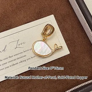 Détail d'un pendentif en forme de baleine en nacre naturelle et cuivre plaqué or.
