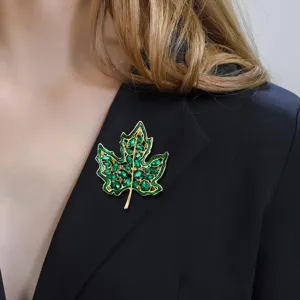 Elegante broche de hoja de arce de cristal verde con borde dorado en un blazer negro chic