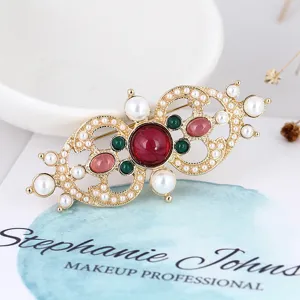 Detail view of a vintage Baroque palace style brooch with colorful gems and pearls.