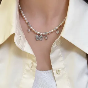 Primo piano di una collana di perle con ciondoli a farfalla e a cuore scintillanti.