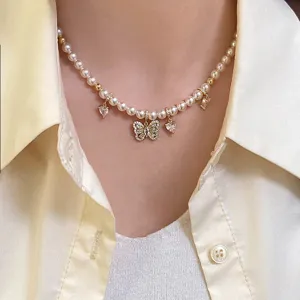 Dettaglio di una collana di perle con ciondolo a farfalla in zirconi micro-pavé