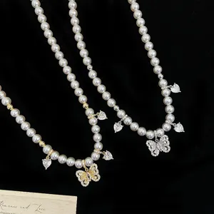 Dettaglio di ciondoli a farfalla in zircone su un'elegante collana di perle per donna
