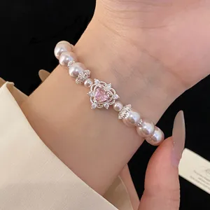 Close-up showcasing the intricate pink heart zircon and shimmering pearls on a wrist.