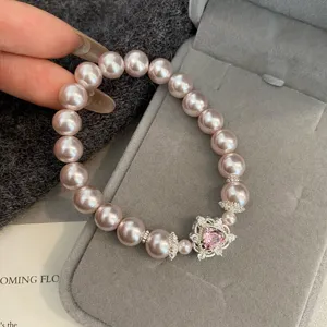 Close-up of pink pearl bracelet with heart-shaped zircon pendant in a jewelry box