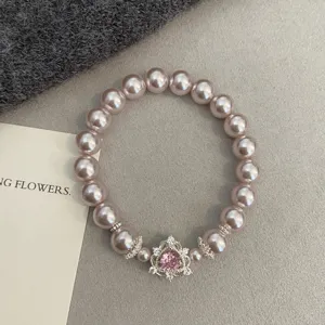 Pink pearl bracelet featuring a heart-shaped zircon pendant on a textured background.