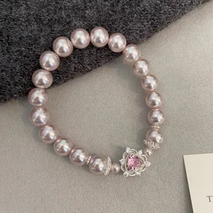 Close-up of elegant pink pearl bracelet with sparkling heart-shaped zircon charm.