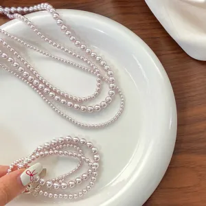Close-up detail of elegant rose pink pearl necklaces and bracelet on a white plate