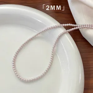 Macro view of 2mm rose pearl necklace elegantly arranged on a classic white ceramic plate