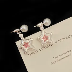 Close-up detail of elegant star-shaped earrings with pink zircon and pearl accents