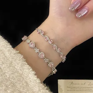 Close-up view of layered silver bracelets featuring pink heart-shaped zircons on wrist