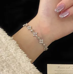 Close-up of elegant four-leaf clover bracelet with pink zircons on wrist.