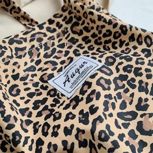 Close-up of Augur brand label on retro leopard print canvas tote bag