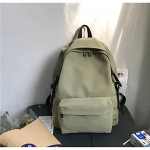 Minimalist solid color nylon backpack with front pocket in a lifestyle setting.