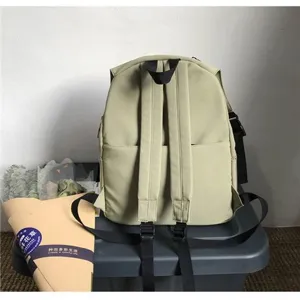 Back view of a minimalist khaki water-resistant nylon backpack with adjustable shoulder straps