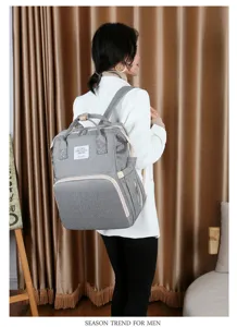 Großer grauer multifunktionaler Wickelrucksack, von einem Modell in Innenräumen getragen