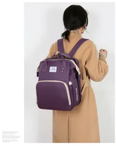 Violetter multifunktionaler Wickelrucksack mit faltbarem Bett am Modell präsentiert