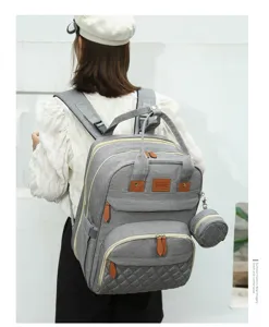 Model wearing a grey multi-purpose mommy backpack with Oxford cloth and leather accents.