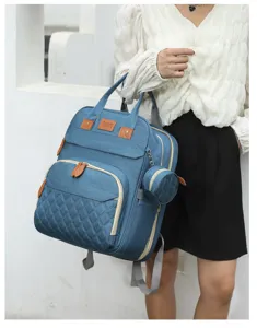 Blue multi-functional diaper bag backpack with quilted detail held by model