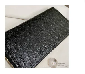 Macro view of black glossy crocodile pattern texture on a long zip-around lady's purse