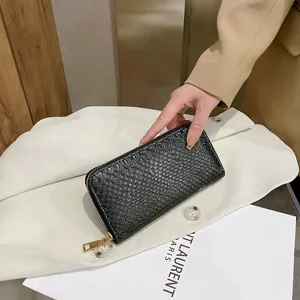 Close-up of a stylish black crocodile pattern long wallet for women with gold zipper