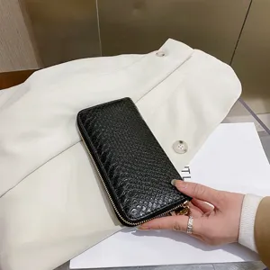 Macro view of black crocodile pattern texture on women's long zip-around wallet clutch