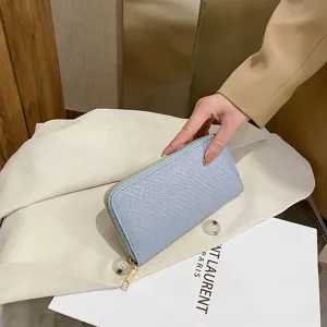 Close-up of light blue women's long wallet with crocodile pattern and gold zipper