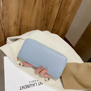 Detailed view of light blue crocodile embossed texture on a women's long clutch wallet.