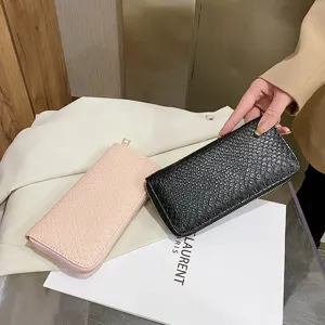Detailed close-up view of elegant crocodile texture long wallets in pink and black colors.