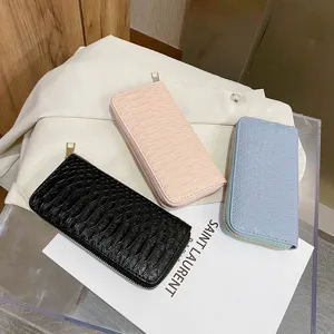 Detailed view of stylish crocodile pattern long zip-around wallets in black, pink and blue