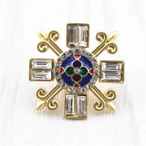Macro detail of a vintage Baroque brooch in matte gold with enamel and shiny crystals