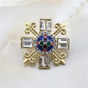Detail of vintage matte gold baroque brooch with colorful enamel and crystal inlays.