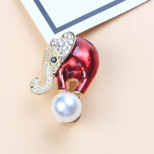 Detail view of a red enamel elephant brooch with crystals and a large white pearl pendant.